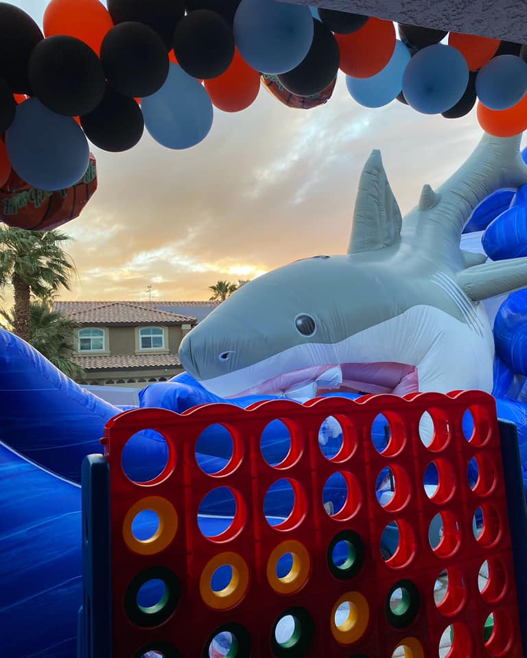 A big Connect Four game in front of a bunch of balloons shaped as an arch and a shark inflatable.