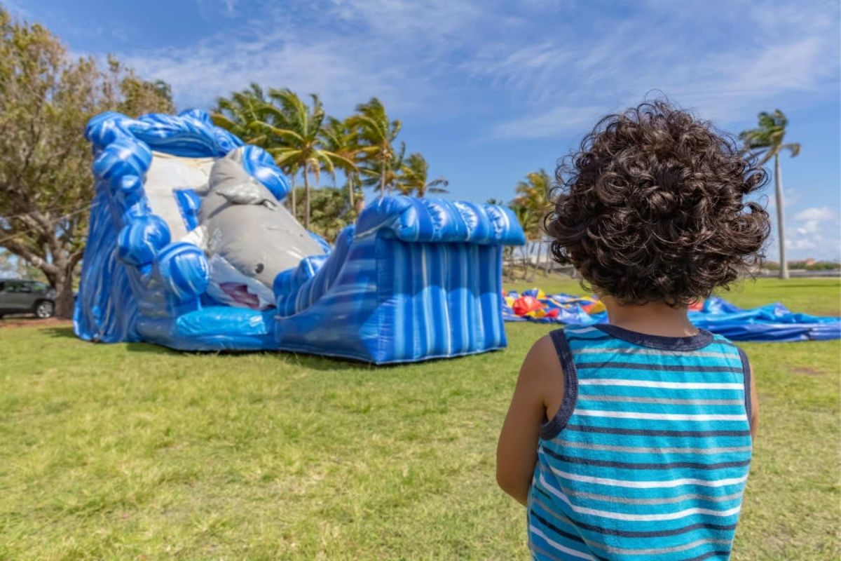 A little boy in front of a big inflatable with a shark on it