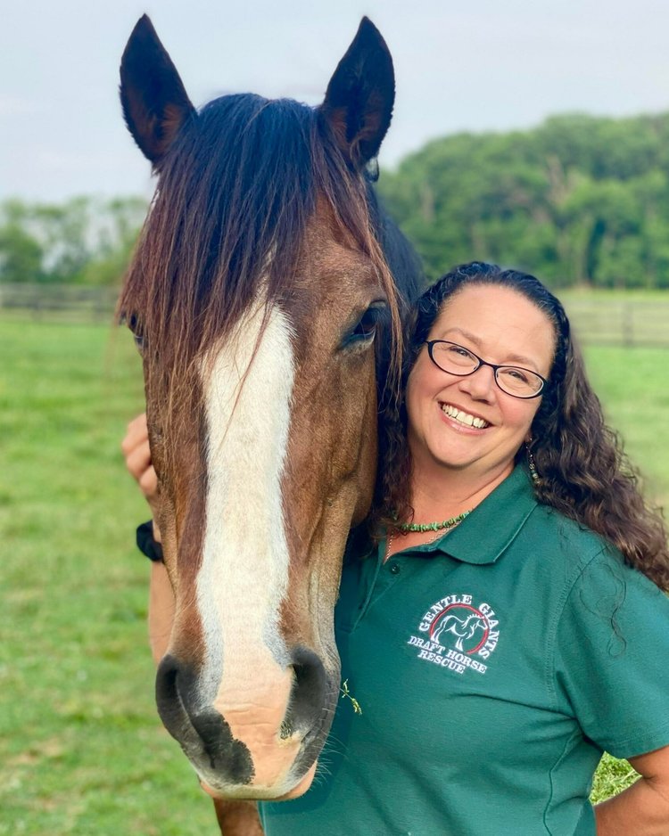 Christine Hajek, Executive Director & Founder of Gentle Giants Draft Horse Rescue, smiling and posing with a horse.